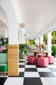Square footstools upholstered in Crémaillère Rosa atop a black and white checkered floor at Coral Sands Hotel, Bahamas. Interior design by Eddie Lee, photography by Brittany Ambridge — a playful, pattern-rich setting with whimsical charm.